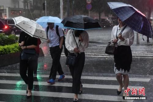 资料图:5月7日,广州街头,民众撑伞行走在雨中。