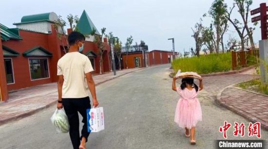 雷先生带着女儿拿生活物资，女儿头顶着新疆大馕饼。　受访者提供