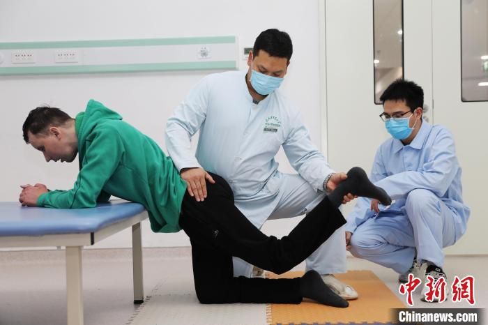 图为康复治疗师正在对阿尔乔姆进行伸髋伸膝训练。西安中医脑病医院供图